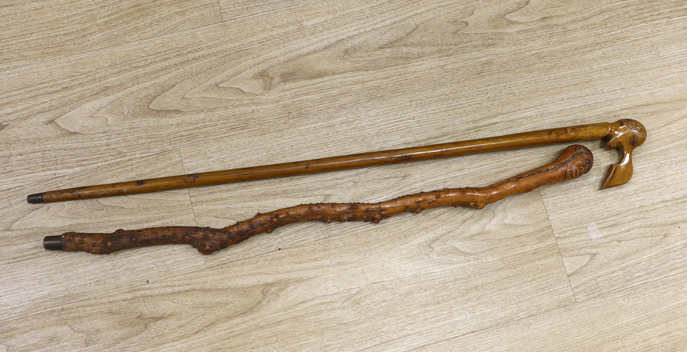 Two walking canes including a Greek olive wood example with carved head handle, largest 89cm in length